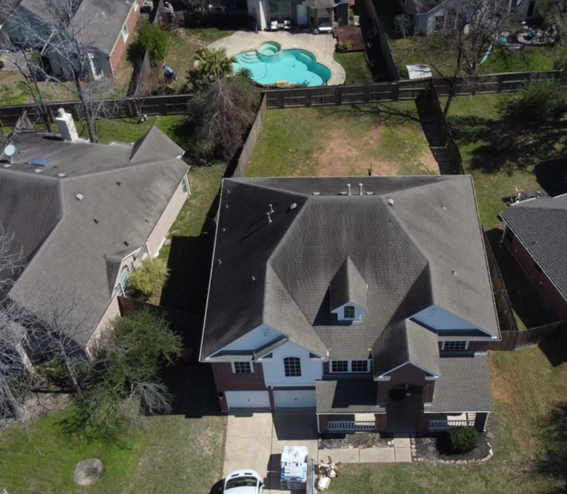 Aerial top-down view of completed residential shingle roof with pool in backyard