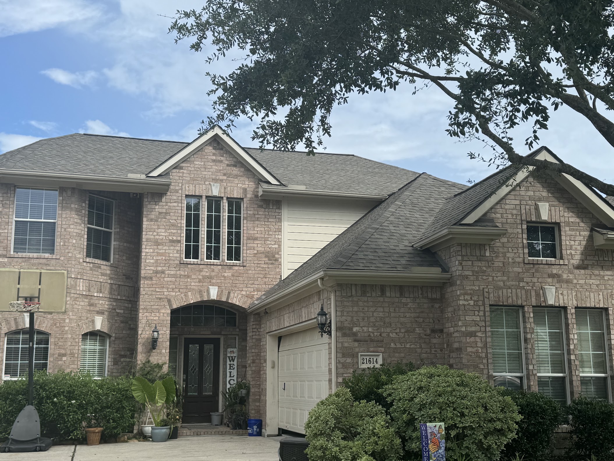 Completed dark shingle roof on large two-story brick residential home