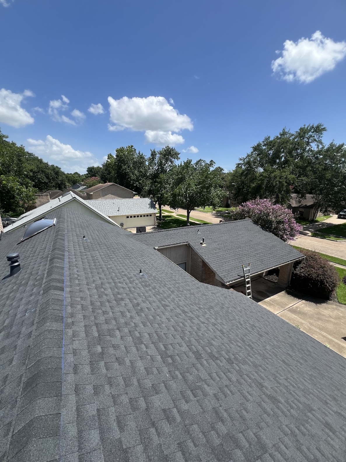 Residential shingle roof installation viewed from roofline with neighborhood in background